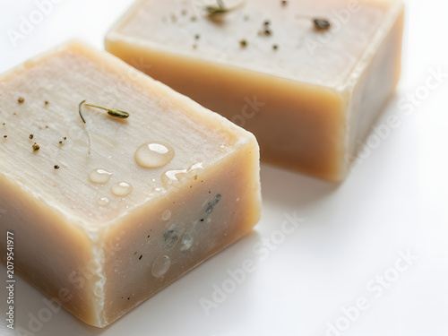 Handmade Soap Bars: Two artisanal soap bars, infused with natural herbs and essential oils, are presented with glistening water droplets, suggesting a gentle and refreshing cleansing experience.