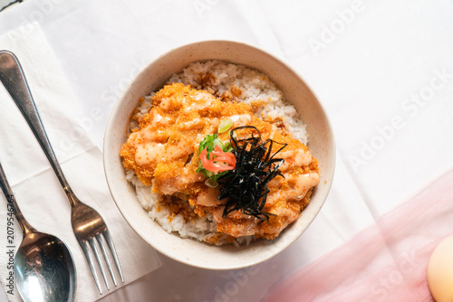 Slika na platnu Savory Delight: A close-up shot reveals a delectable bowl of rice topped with a rich, creamy orange sauce and garnished with fresh herbs and seaweed, ready to be savored