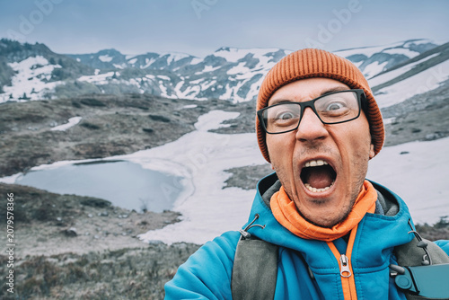 Photography Man creating a selfie outdoor portraying shock and excitement in a challenging w