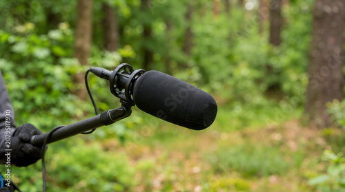 Obraz na płótnie Shotgun microphone with foam windscreen on a boom pole. Outdoor audio recording in a forest