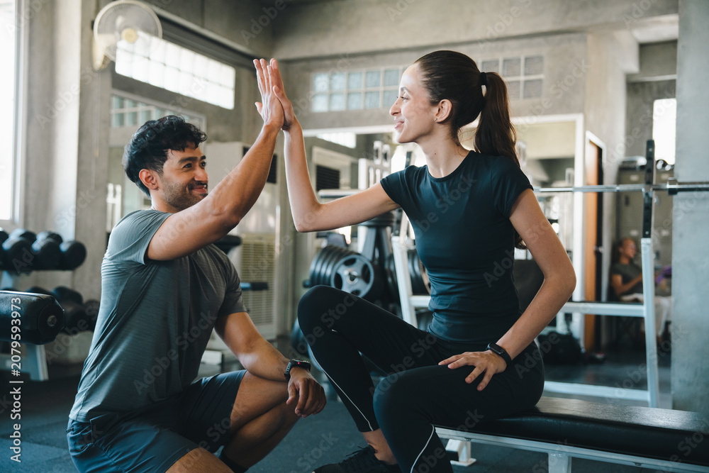 Obraz premium Couple gym fitness workout high five woman man exercise support cheerful athletes sharing high five during training session in modern health club