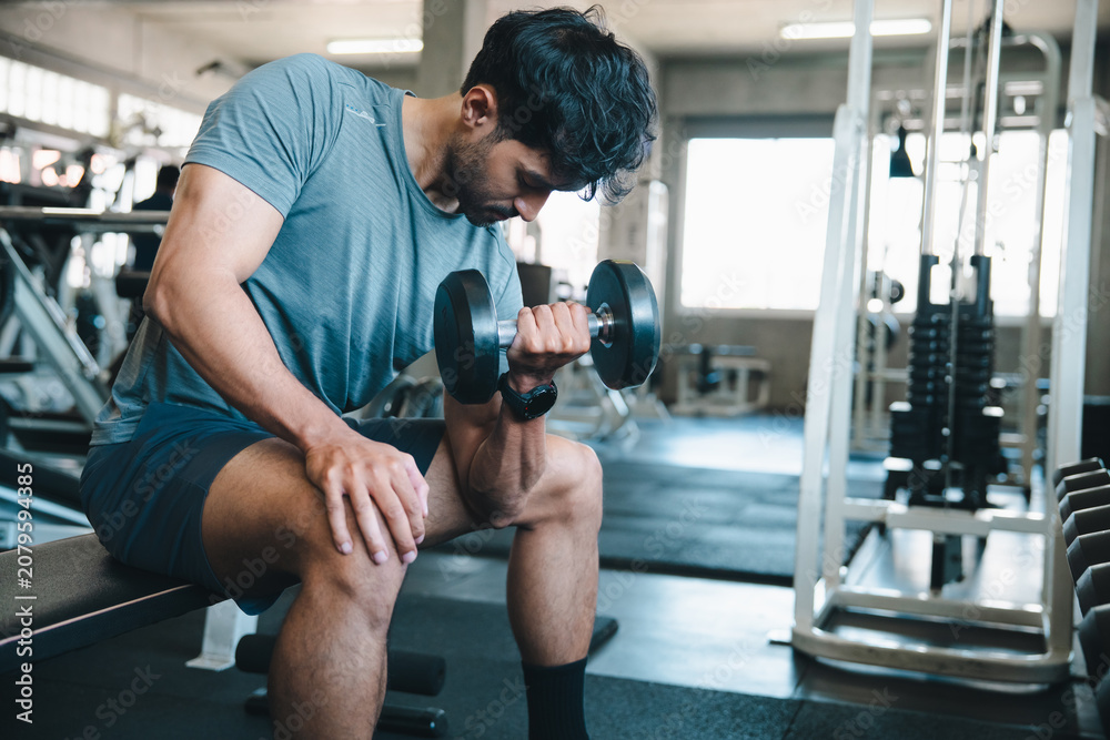 Fototapeta premium Man dumbbell gym exercise fitness bench muscle workout man lifting dumbbell on bench inside modern gym with focused expression and athletic training routine