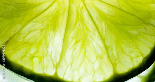 Foto Macro Close-up of Fresh Lime Slice Texture,A vibrant, high-resolution macro shot highlighting the intricate, translucent cell structure and juicy pulp details of a fresh lime slice, illuminated from