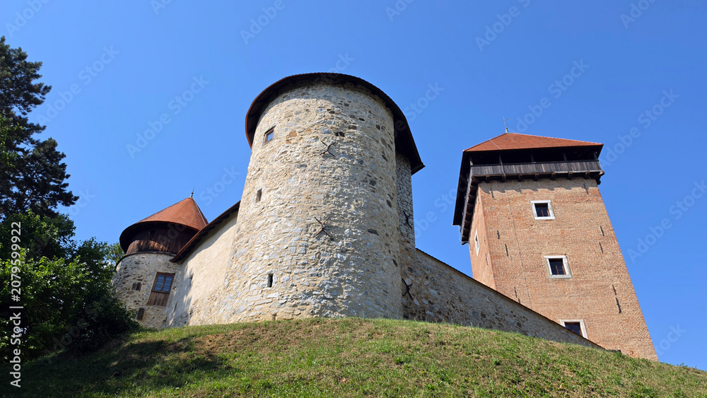 Fototapeta premium Medieval stone fortress with a large round bastion and a tall square brick watchtower