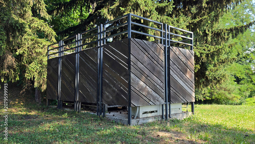 Outdoor waste container enclosure with diagonal wooden slats in public park