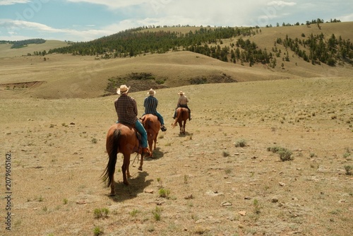 Obraz na płótnie Cowboys horseback riding across open prairie in Colorado, USA