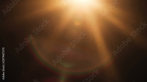 Golden optical lens flare light leak with sun rays and dust particles on dark background