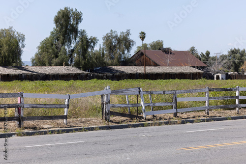 Tablou pe pânză A decaying fence frames a field and barn in Hemet, California, USA