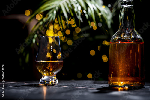Obraz na płótnie Glass of scotch whisky and unlabelled glass bottle on dark marble surface