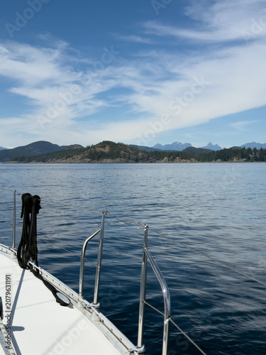 Scenic view of coastal mountains and calm ocean from a sailboat deck