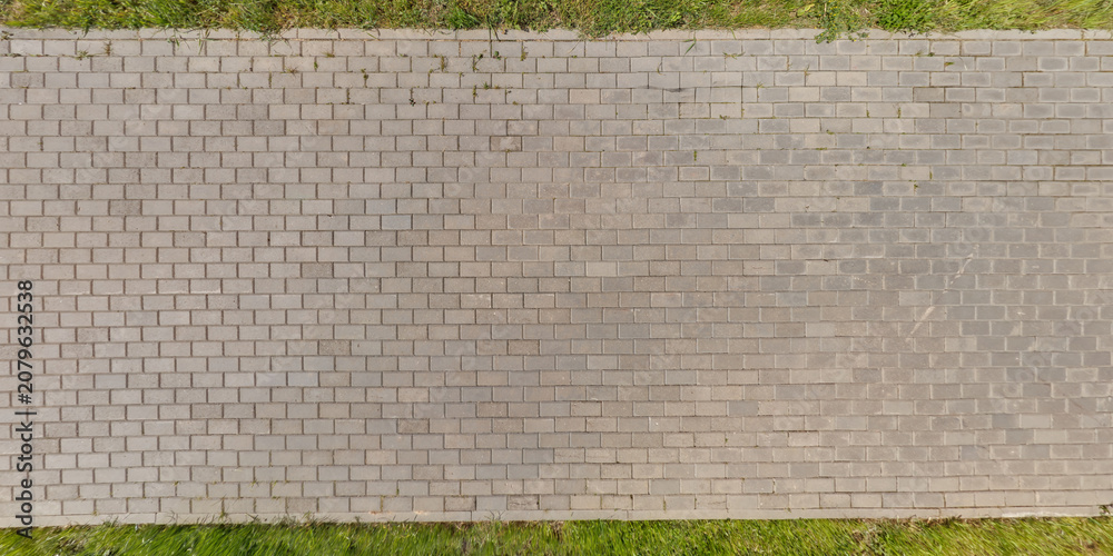 Fototapeta premium top view of surface of pedestrian path with paving slabs with the border of light and shadow