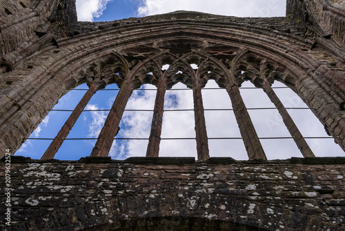 Obraz na plátne Dramatic view of the roofless nave and arched window frames of Tintern Abbey, a historic Cistercian monastery ruin in Wales