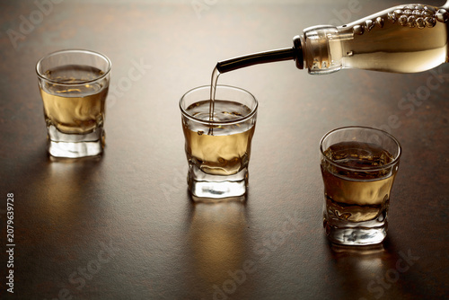 Tableau sur toile Whiskey pour from a bottle into a small glasses.