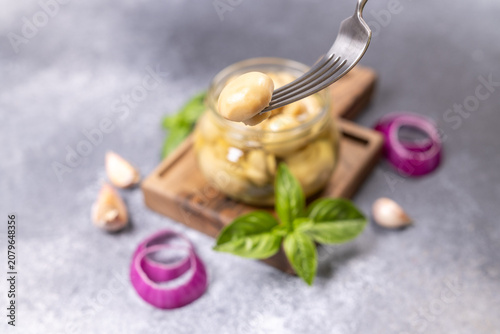 Picking pickled marinated mushrooms from glass jar