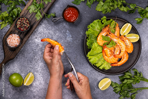 Person peeling cooked shrimp for seafood meal