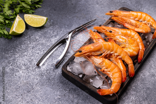 Cooked king prawns on ice with lime and parsley
