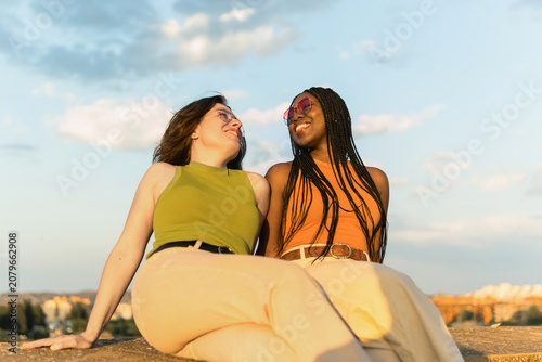 Bild auf Leinwand Diverse women laughing together enjoying golden hour