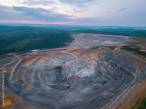 Fotografie Aerial view of expansive open pit mine at dusk with surrounding landscape