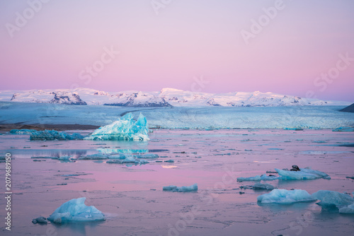 Bild auf Leinwand Blue icebergs floating in Jokulsarlon glacial lagoon at pastel sunset