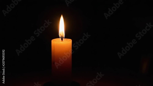 A single lit candle glowing in the dark against a black background