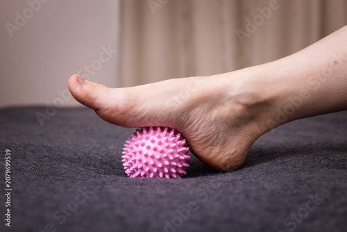 Photos Foot pressing a pink spiky ball on a dark surface, close-up of a tactile moment,