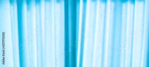 Soft light blue curtain with flowing vertical folds and diffused natural light. Minimalist textile background perfect for interior design, home decor and abstract visual compositions.