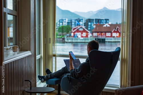 Fotografie Remote Worker with Laptop and Phone Overlooking Lofoten Islands Norway