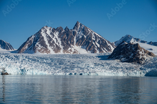 Φωτογραφία Glacier meeting the Arctic Ocean at the base of rugged mountains in Bjornfjorden