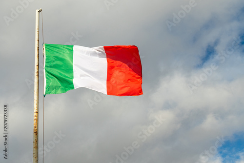 Italy national tricolor flag fluttering in the wind against clouds
