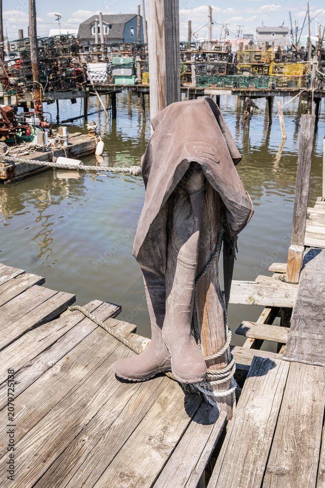 Obraz premium Pair of waders hanging on a pole on a wooden fishing dock