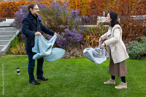 Couple prepares blankets in a park during autumn for a comfortable outdoor gathering