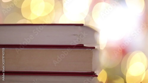 stack of books close-up against a background of golden bokeh. Cozy reading. Book blog wallpaper. 4k footage