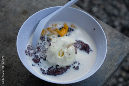 black sticky rice porridge topped with vanilla ice cream and sliced jackfruit. bubur ketan hitam.