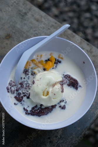 black sticky rice porridge topped with vanilla ice cream and sliced jackfruit. bubur ketan hitam.