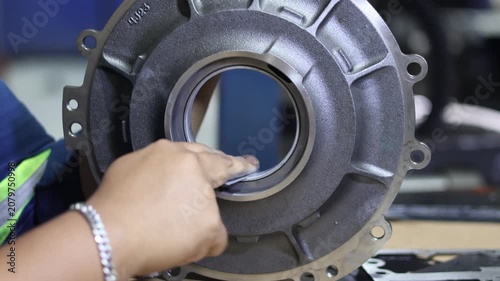 Close up of a mechanic hands using sandpaper to sand and smooth the inner bore of a round metallic automotive casing component during a vehicle overhaul repair.