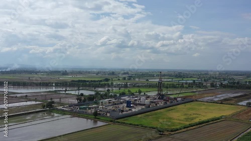 Oil and gas a land rig, onshore drilling rig, in the middle of a rice field aerial view from a drone