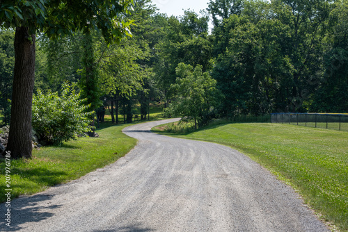 Winding gravel country road through a lush green summer park