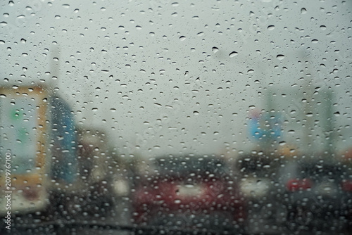 Photos Raindrops on car windshield obscuring traffic and city buildings in the backgrou