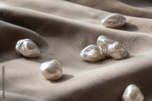 Картината върху платно Irregular pearl nodules scattered on velvet fabric in close-up with soft texture and shallow depth
