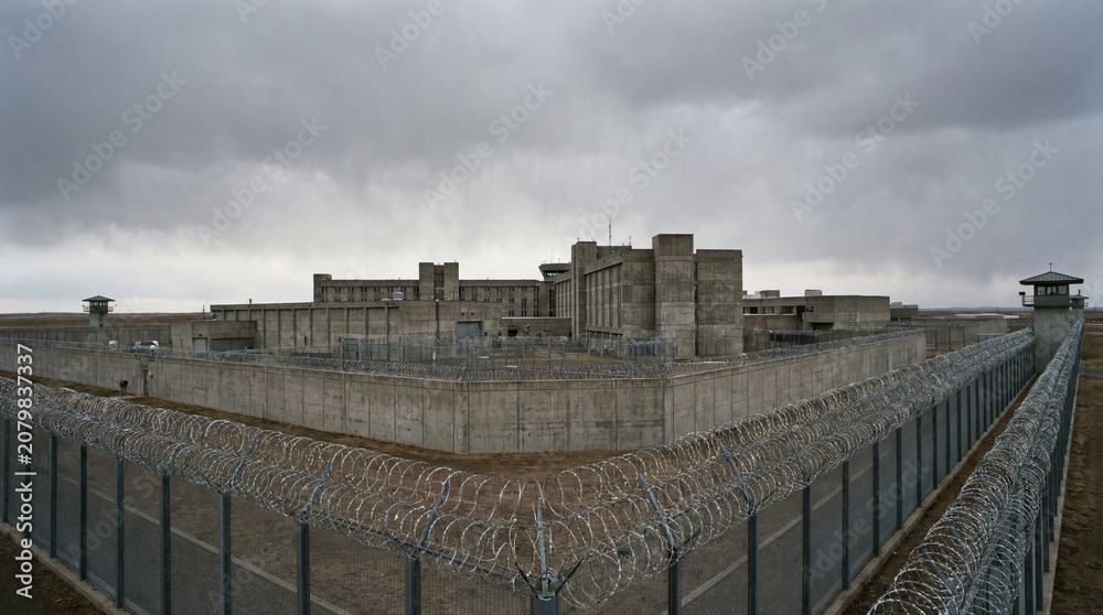 Obraz premium Imposing prison facility exterior compound heavily surrounded by dangerous razor wire fencing without any humans