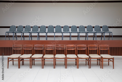 Two rows of neat, elegant chairs in a spacious, pristine, yet empty room, arranged in two rows. 