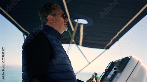 Mature man steering yacht at sea during sailing trip