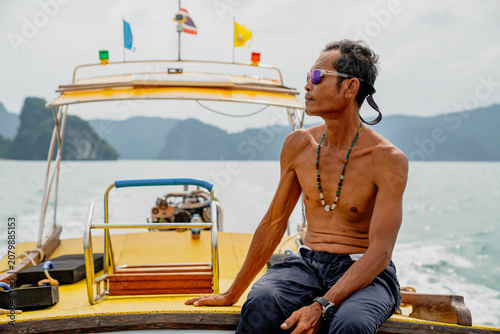 Photography Thai longtail boatman navigating tropical sea with islands