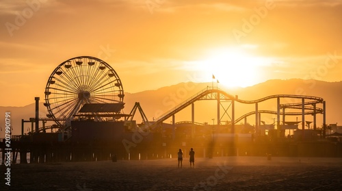 Amusement park pier and couple silhouetted at hazy golden sunset