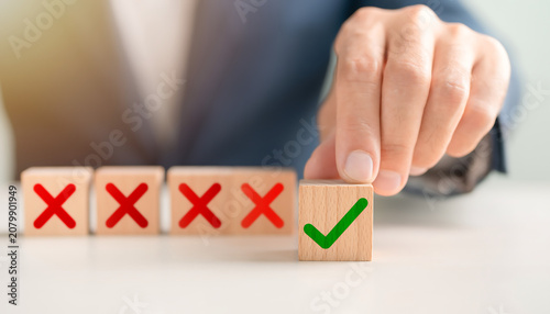 Hand selecting a wooden block with a green tick sign among red cross icons for approval concept With Ai. 
