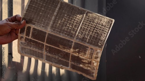 Closeup cropped shot of unrecognizable man examining holding dusty air conditioner filter in hands before cleaning at home. Concept for maintenance of hygiene and pure air to prevent allergies.