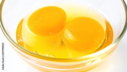 Raw egg yolks in glass bowl.