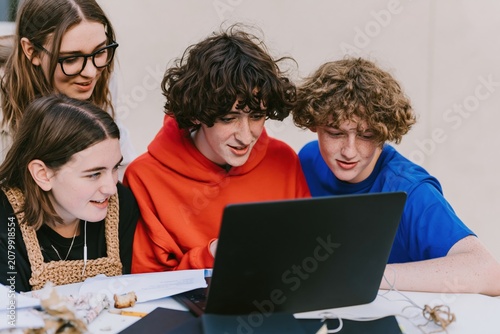 Diverse group of teenage students collaborating around a laptop for education and teamwork imagery, featuring soft matte textures and overcast light