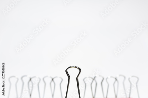 Fotografie Minimal business concept showing a single binder clip in sharp focus standing apart from a blurred group in the background