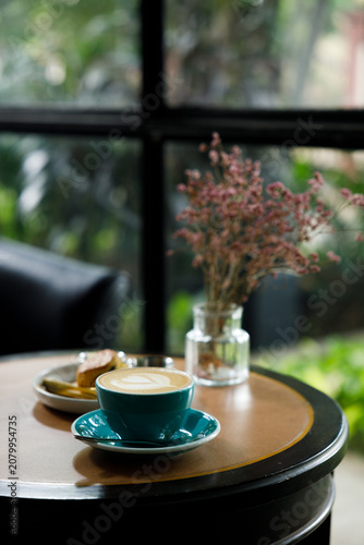 Cup of hot latte coffee on table by the window.